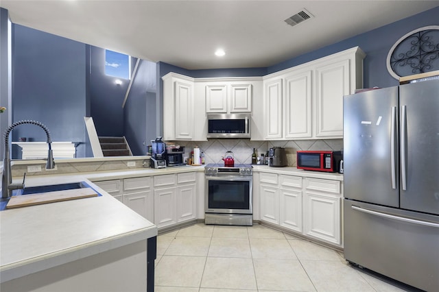 kitchen with visible vents, a sink, appliances with stainless steel finishes, light countertops, and light tile patterned floors