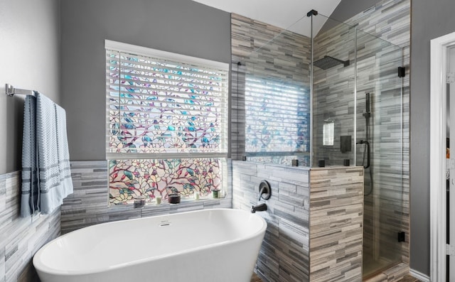 full bath featuring a soaking tub, a shower stall, and tile walls