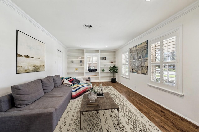 living area featuring visible vents, built in features, wood finished floors, crown molding, and baseboards