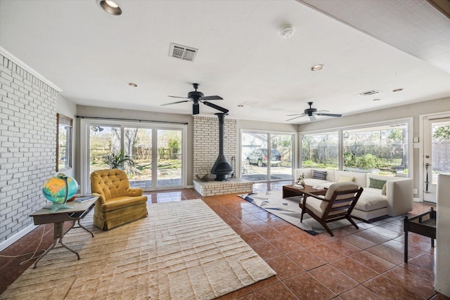 sunroom / solarium with visible vents, a ceiling fan, and a wood stove