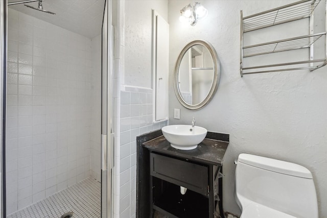 full bathroom featuring a stall shower, toilet, vanity, and a textured wall