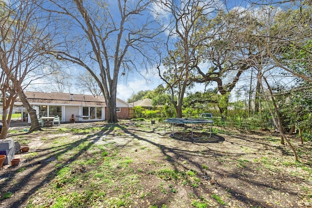 view of yard with a patio, a trampoline, and fence