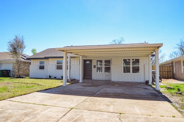 view of front facade featuring a carport, board and batten siding, brick siding, and a front lawn