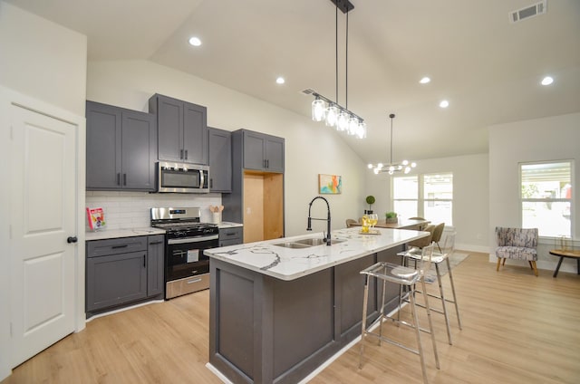 kitchen featuring light stone counters, visible vents, a sink, stainless steel appliances, and tasteful backsplash