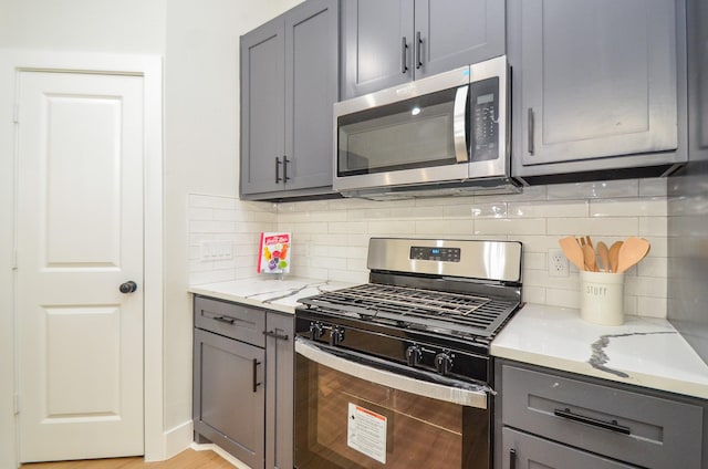 kitchen with backsplash, appliances with stainless steel finishes, and gray cabinets