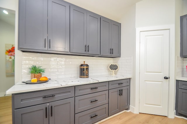 kitchen featuring backsplash, gray cabinetry, and light wood finished floors