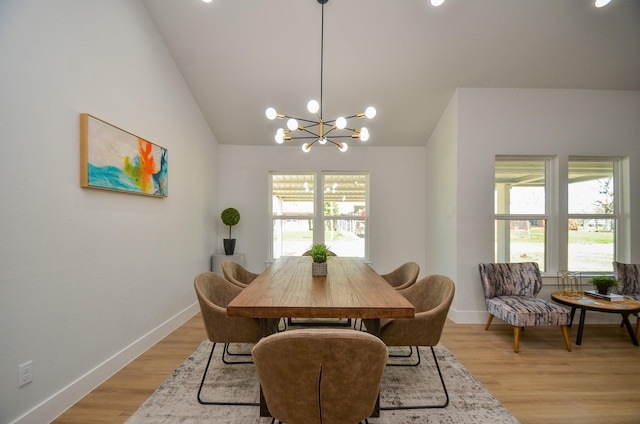 dining space with an inviting chandelier, light wood-style floors, a wealth of natural light, and vaulted ceiling