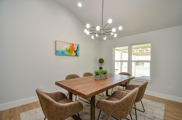 dining room featuring a chandelier, light wood finished floors, baseboards, and vaulted ceiling