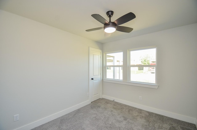 carpeted empty room featuring baseboards and a ceiling fan