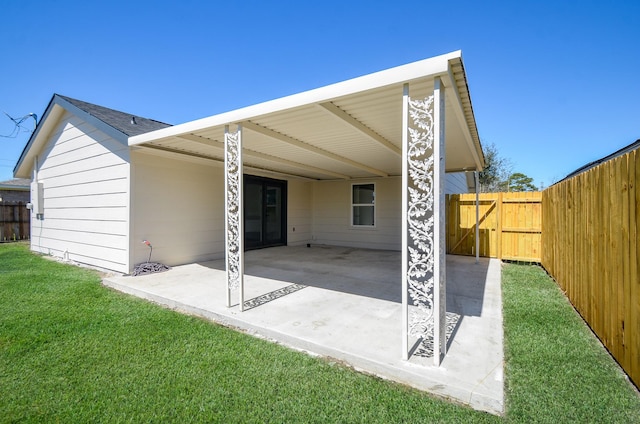 rear view of house featuring a patio, a gate, fence, a carport, and a lawn