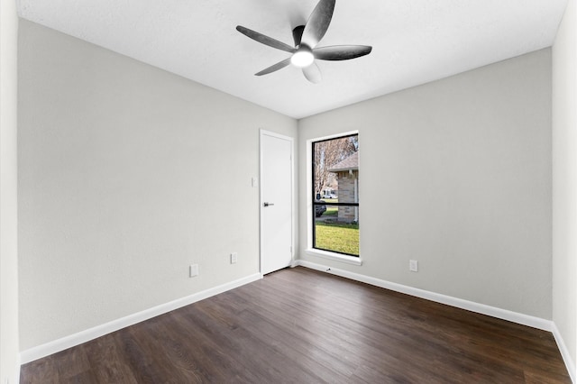 empty room featuring baseboards, dark wood-style flooring, and a ceiling fan