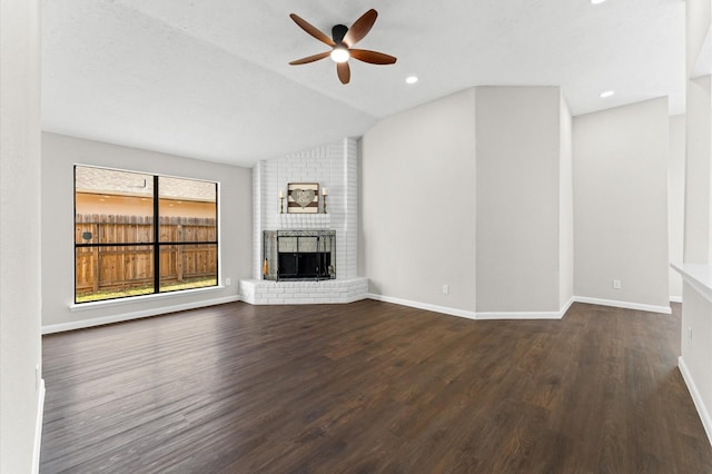 unfurnished living room featuring a ceiling fan, wood finished floors, a fireplace, baseboards, and vaulted ceiling