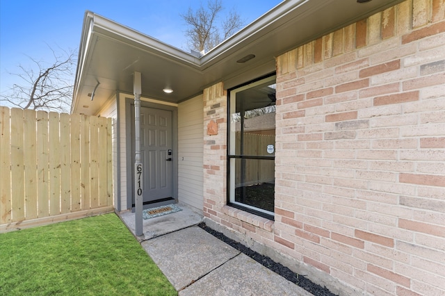 entrance to property with brick siding and fence