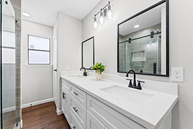 full bath with baseboards, wood finished floors, a stall shower, and a sink