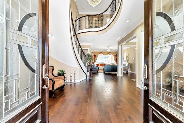 entrance foyer with dark wood-style floors, crown molding, baseboards, a towering ceiling, and stairs