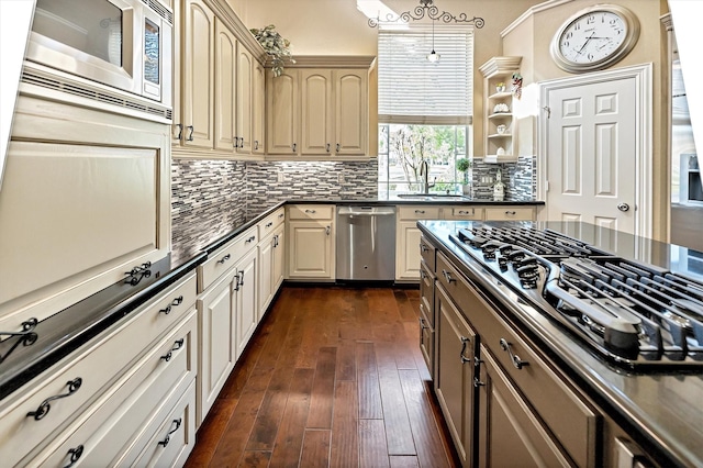 kitchen with a sink, stainless steel appliances, dark countertops, and dark wood-style floors