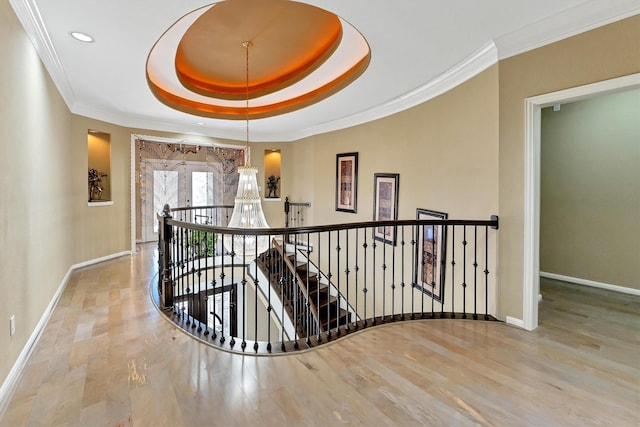 corridor with baseboards, an upstairs landing, a raised ceiling, and ornamental molding