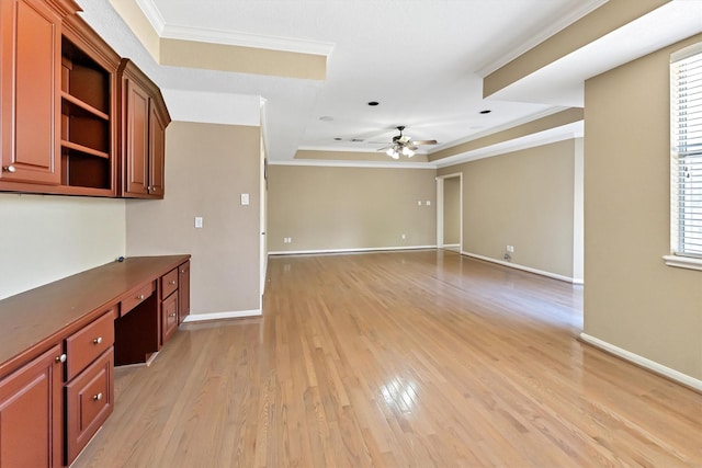 interior space with ornamental molding, built in desk, light wood finished floors, and ceiling fan