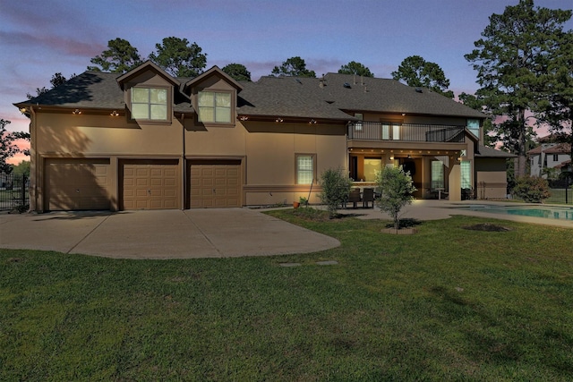 view of front of property with a front lawn, concrete driveway, stucco siding, a garage, and a balcony