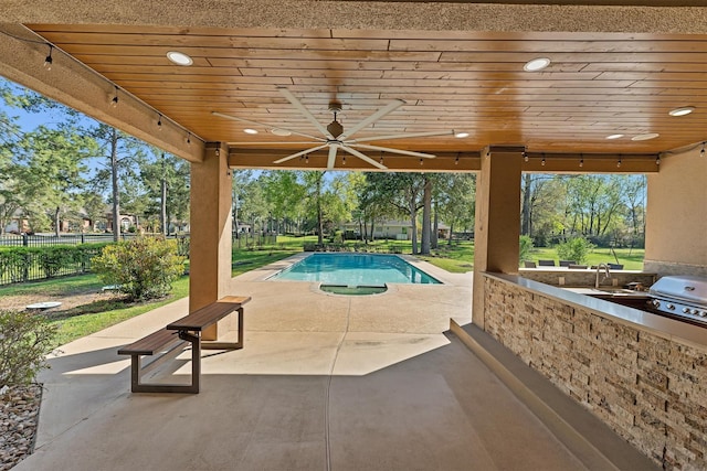 view of pool with fence, exterior kitchen, a fenced in pool, ceiling fan, and a patio area