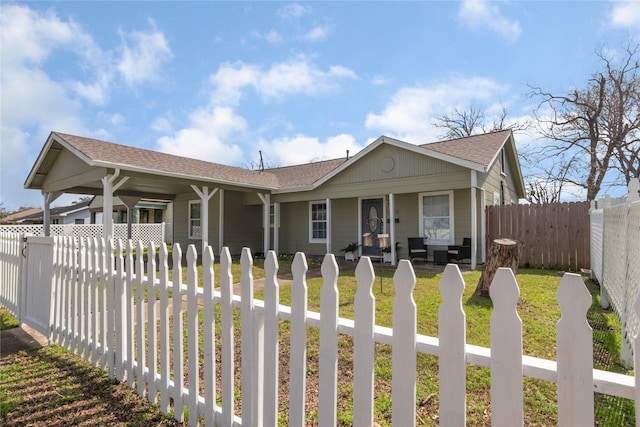 view of front of property featuring a front lawn, covered porch, a fenced front yard, and a shingled roof