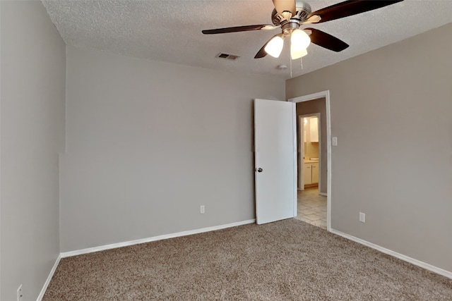 carpeted spare room with baseboards, a ceiling fan, visible vents, and a textured ceiling