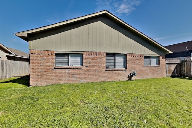 rear view of property with a lawn, brick siding, and a fenced backyard