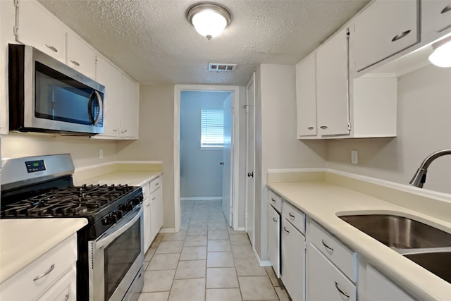 kitchen with a sink, stainless steel appliances, visible vents, and white cabinetry