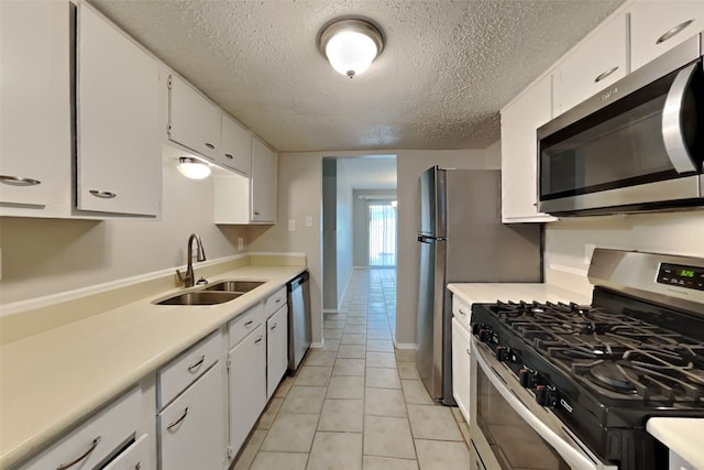 kitchen featuring appliances with stainless steel finishes, white cabinetry, light countertops, and a sink