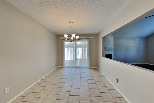 empty room with baseboards, a chandelier, light tile patterned floors, a fireplace, and a textured ceiling