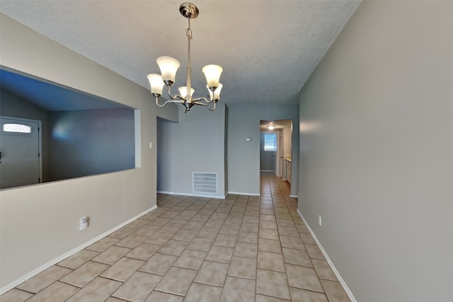 empty room featuring visible vents, baseboards, a chandelier, light tile patterned floors, and a textured ceiling