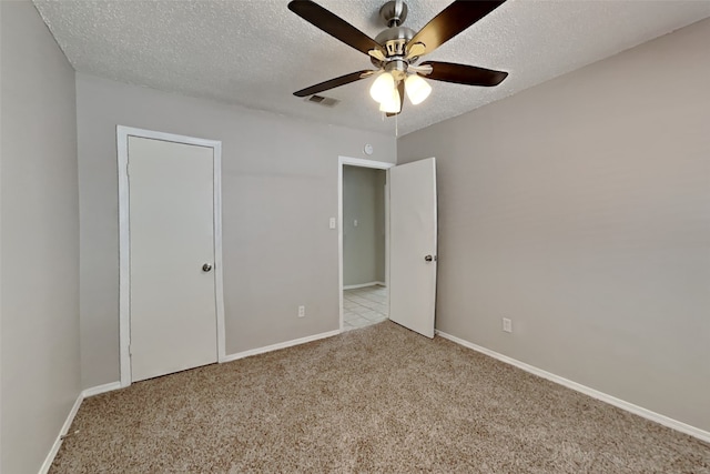 unfurnished bedroom with visible vents, baseboards, carpet flooring, a textured ceiling, and a ceiling fan