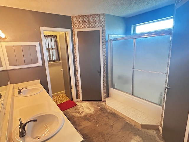 full bath featuring double vanity, a textured ceiling, and a sink