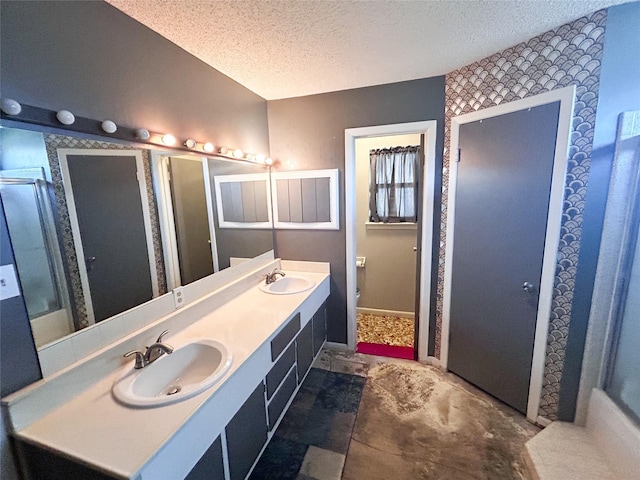 full bathroom with a sink, baseboards, a textured ceiling, and double vanity