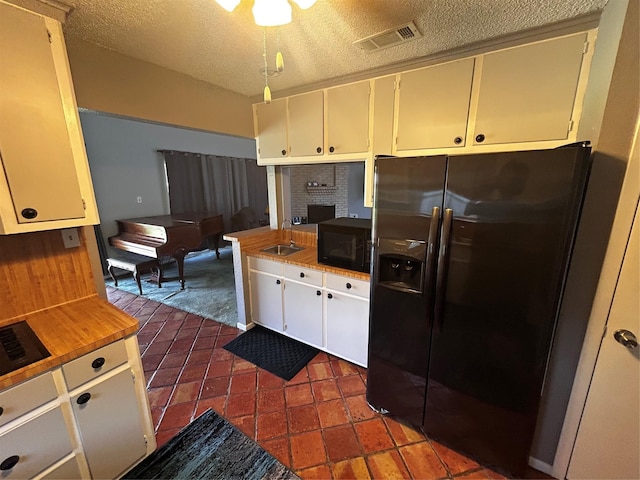 kitchen featuring a sink, visible vents, a textured ceiling, and black appliances