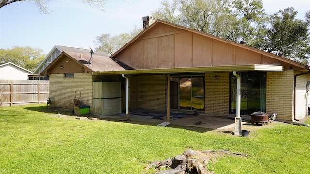 back of property with a lawn, fence, brick siding, and a chimney