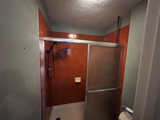 full bathroom with a textured ceiling, a shower stall, and a textured wall