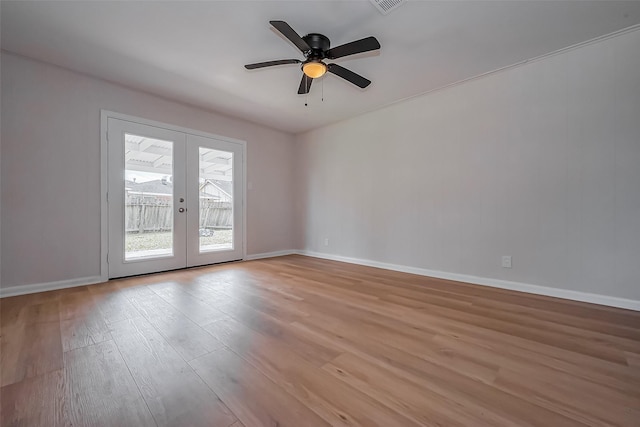 spare room featuring french doors, baseboards, light wood-style flooring, and a ceiling fan