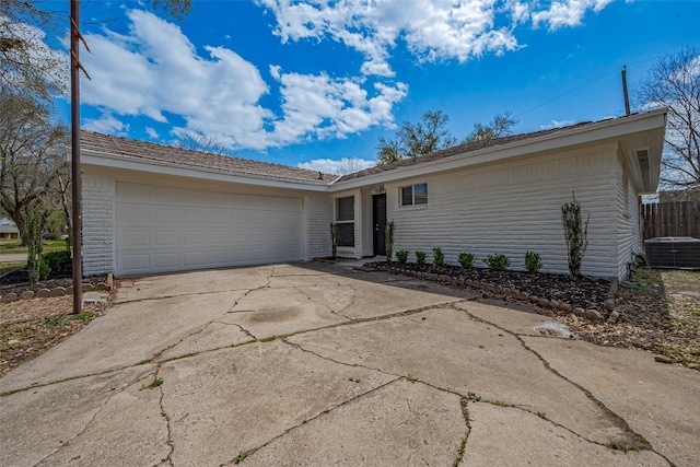 ranch-style home featuring concrete driveway, a garage, and fence