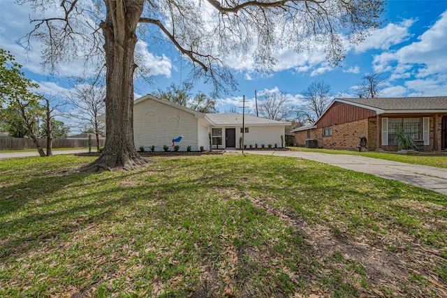 view of front of house featuring brick siding, concrete driveway, a front yard, and fence