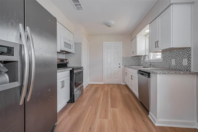 kitchen with white cabinetry, visible vents, appliances with stainless steel finishes, and a sink