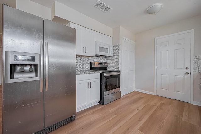 kitchen featuring visible vents, light wood-style flooring, stainless steel appliances, white cabinets, and decorative backsplash