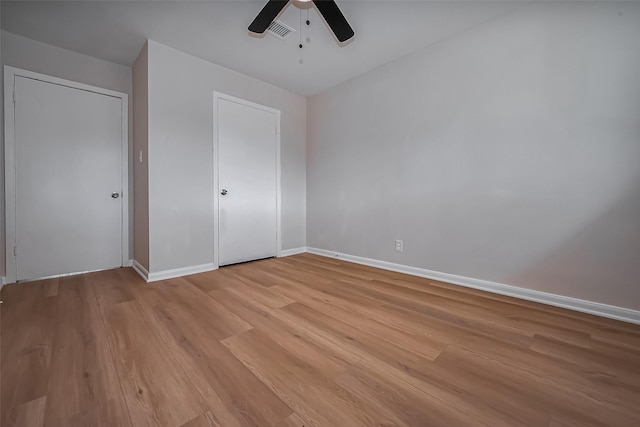 unfurnished bedroom featuring a ceiling fan, light wood-style flooring, baseboards, and visible vents