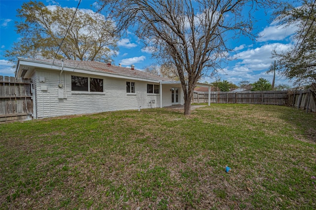 rear view of house with a lawn and a fenced backyard