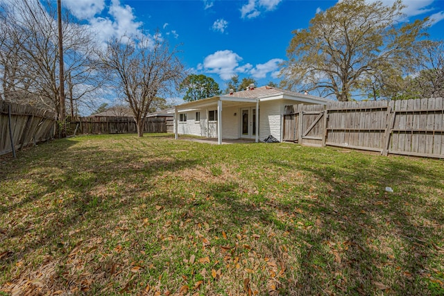 view of yard with a patio area, french doors, a fenced backyard, and a gate