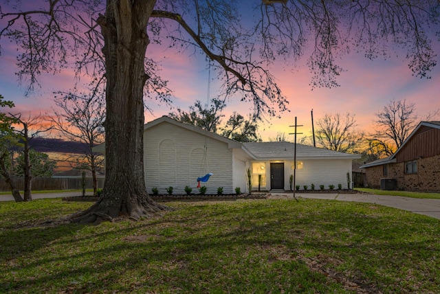 mid-century modern home with driveway, central AC, and a yard