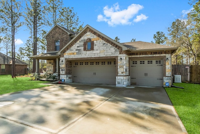 view of front of home featuring fence, concrete driveway, a front yard, stone siding, and an attached garage