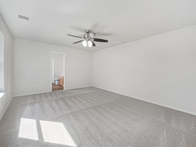 carpeted empty room with baseboards, visible vents, and ceiling fan