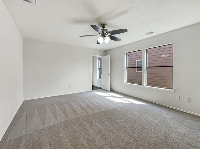 carpeted spare room featuring visible vents, baseboards, and a ceiling fan