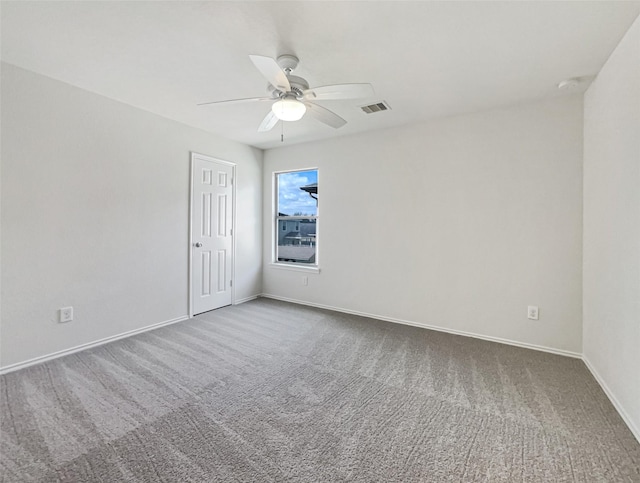 carpeted empty room featuring baseboards, visible vents, and ceiling fan